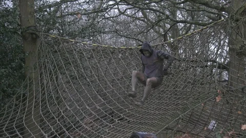 An obstacle course racer climbs over a cargo net Stock Footage 112003523