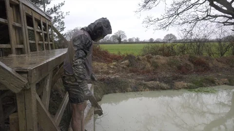 An obstacle course racer jumps off an obstacle into a freezing cold pond Stock Footage 112004909