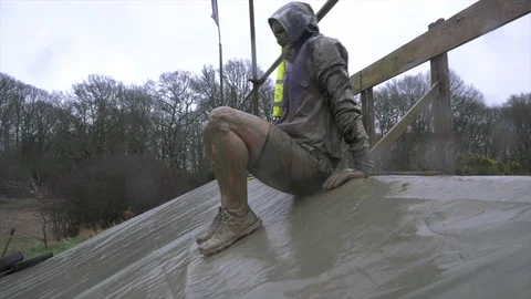 An obstacle course racer slides into a cold, muddy pond 動画素材 112006357
