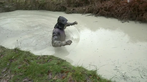 Obstacle course racer wades through waist deep, freezing cold water Stock Footage 112006439