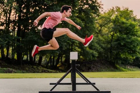 Obstacle course runner jumping a hurdle during outdoors training Foto stock