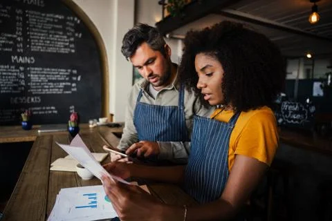 Occupied business co-workers sorting out bank statements for the week working at Stock Photos