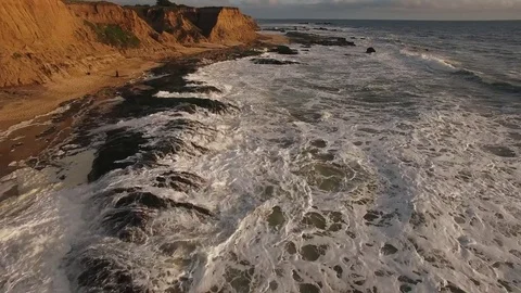Ocean and waves with sandy cliff aerial Stock Footage