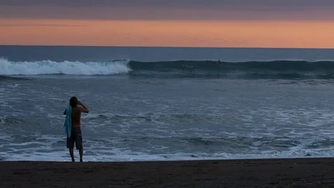 Ocean beach break surfing in magic hour with photographer taking pictures Stock Footage 107795317