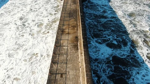 Ocean beats lighthouse base making foam against horizon Stock Footage 124993861