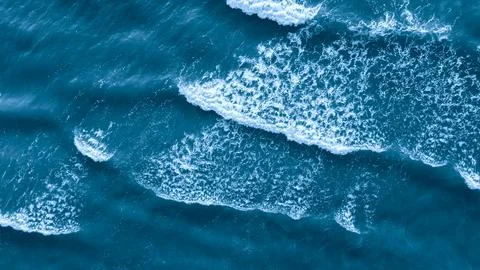 Ocean is blue and has waves as a flat textured blue background top view for w Stock Photos