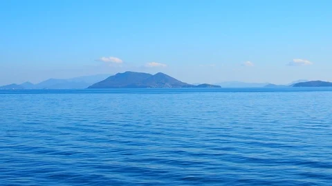 Ocean clam sea surface with small island mountain, clear sky Stock Footage 100652069