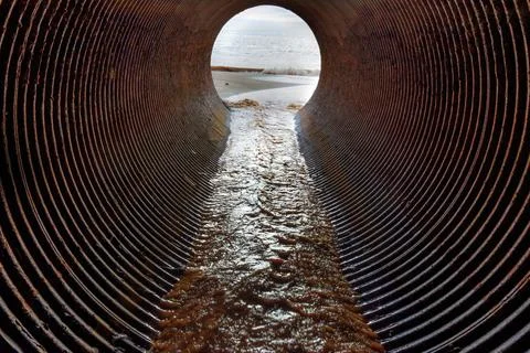 Ocean coast view seen through the drainage pipe Stock Photos