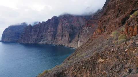 Ocean deep blue waves crash into the black volcanic shore of Tenerife. Cinematic Stock Footage 207235789