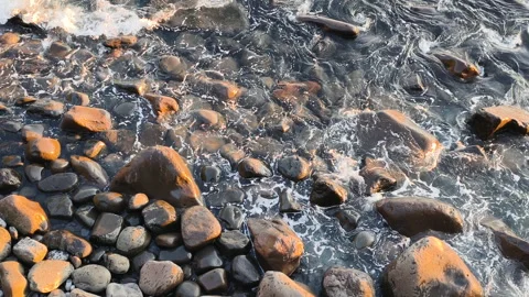 Ocean dynamics meet dark coastal geology. Wave energy shapes volcanic rocks Stock Footage 325022663