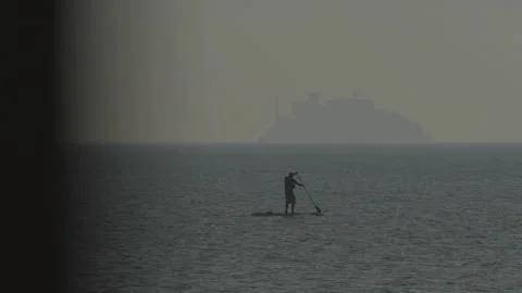 Ocean foreground with person rowing left to right and island, San Francisco Stock Footage 333578311