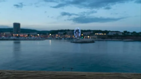 Ocean Harbor with an Ferris wheel in the background while a boat passes by Stock Footage 231368304