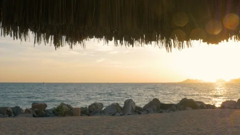 Ocean Horizon at Sunset Framed by Palm Thatch Umbrella and Room for Text in 4k Stock Footage 101266145