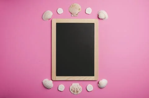 Ocean inspired flat lay composed of a blackboard, sea shells on pink Foto stock