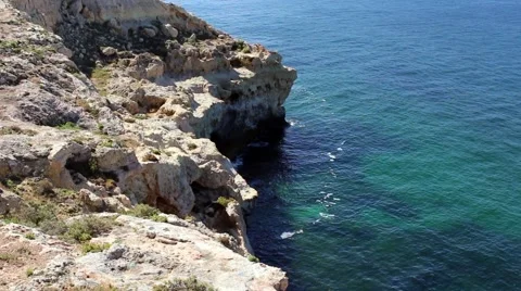Ocean laps rocks below steep cliffs. Stock Footage 65015671
