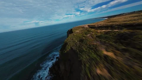 Ocean meets cliff under golden sky Stock Footage 340905187