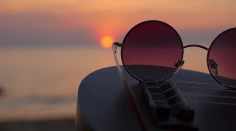 Ocean or Sea Sunset Through Hippie Sunglasses Lying on Ukulele Stockbeeldmateriaal 66546342