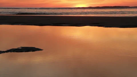 Ocean reddish sunset. Low tide, puddles reflecting the sky and waves Stock Footage 285166268