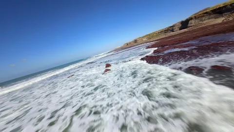 Ocean rolls over vibrant red shoreline Video stock 346077519