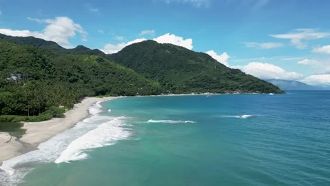 Ocean rolls waves to sandy beach against tropical hills Stock Footage 247422721