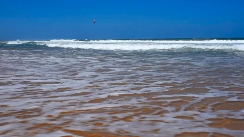 Ocean sandy beach with high waves and kite surfer in the distance Stock Footage 72134724