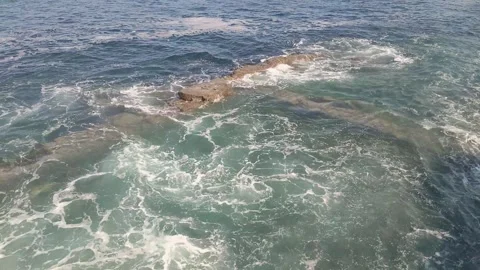 A ocean scene where strong waves crash against a nearly submerged rock wall Stock Footage 305307648