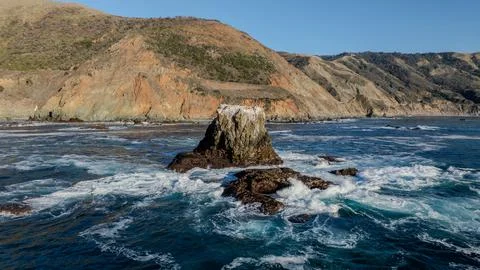 Ocean Sea Stack with Rugged Coastal Hills in Warm Light Stock Photos