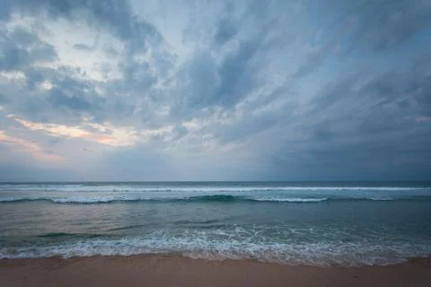 Ocean shore during sunset with cloudy sky Stock Photos