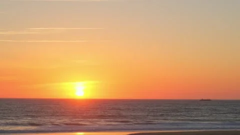 Ocean shore with rolling waves with an orange sun on the horizon while suns.. Stock Footage 264927534