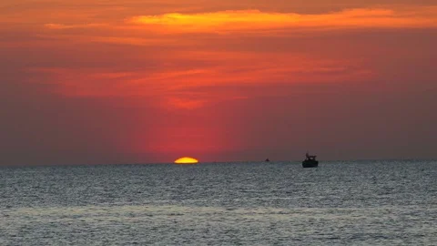 Ocean sunset last seconds, sun hiding behind horizon, dramatic red sky Stock Footage 129657058