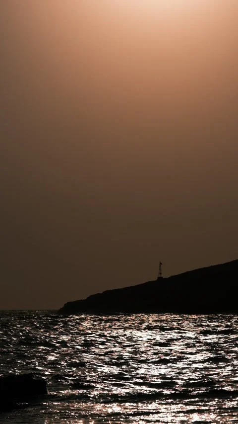 Ocean sunset with lighthouse and hill in the background. Stock Footage 151125098