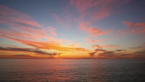 An ocean sunset with vibrant clouds and a peaceful horizon in 4K Stock Footage 283460508
