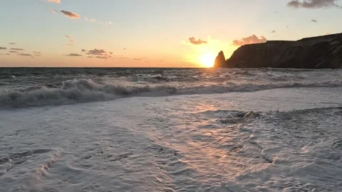 Ocean sunset waves crashing on shore with dramatic cliffs and beautiful light Stock Footage 318445124