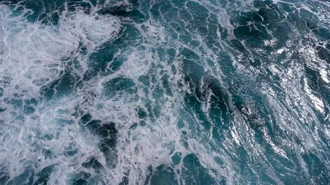 Ocean surface foaming from waves, texture and shape of sea water, aerial view Stockfoto's