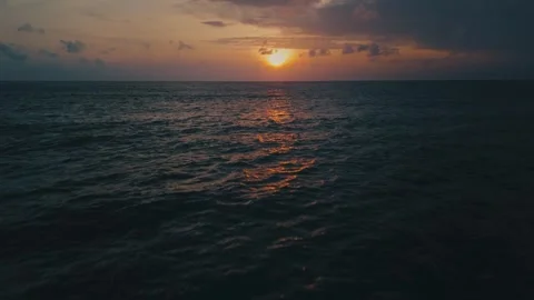 Ocean surface glowing with first light. Golden sunset light reflecting on dark Stock Footage 312748144