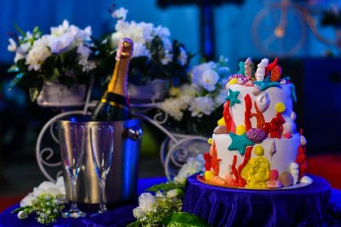 Ocean themed birthday cake with champagne and white flowers in the background Stock Photos