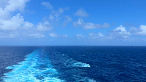 Ocean trail behind a moving ship under blue sky and scattered clouds Stock Footage 309469644