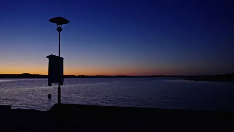 Ocean Twilight with Silhouetted Lamp Post and Distant Land, 120fps Stock Footage 310518529