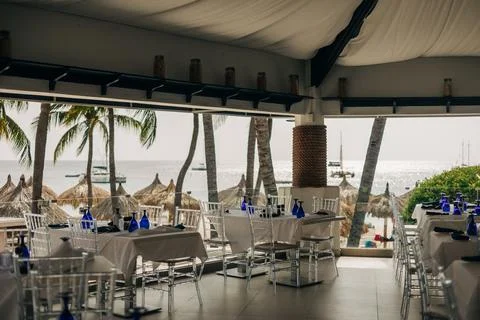 Ocean view dining area with elegant decor and palm trees during daytime Stock-Fotos