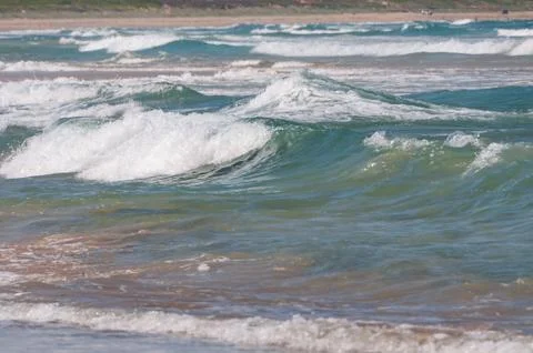 Ocean view with rough waves and sandy beach on the background Stock Photos