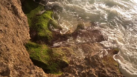 Ocean water breaks on rocks on bright sunny day 動画素材 108792633