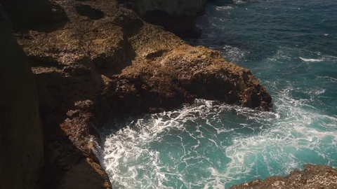 Ocean water breaks on rocks on bright sunny day Stock Footage 108793138