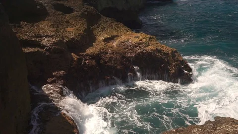 Ocean water breaks on rocks on bright sunny day Stock Footage 108793571