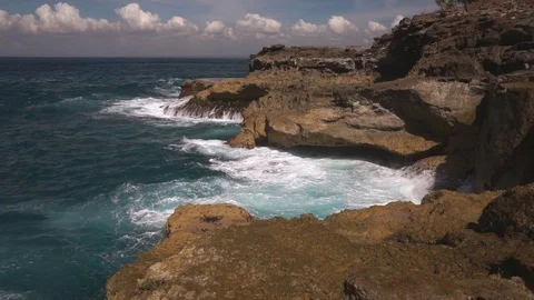 Ocean water breaks on rocks on bright sunny day Stock Footage 108794661