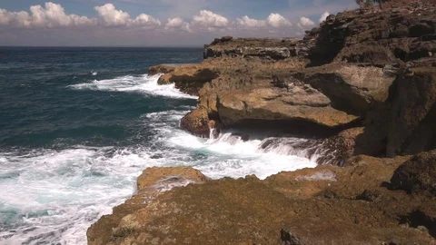 Ocean water breaks on rocks on bright sunny day Stock Footage 108794712