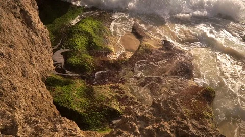Ocean water breaks on rocks on bright sunny day Stock Footage 108794822