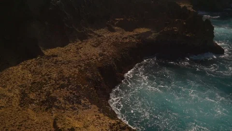 Ocean water breaks on rocks on bright sunny day Stock Footage 108796559