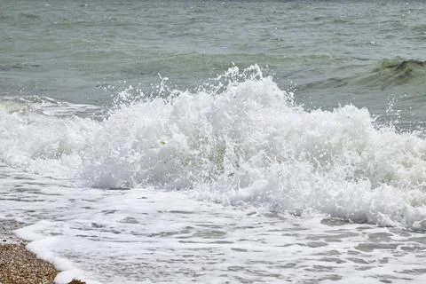 Ocean wave breaking on beach creating white foam splash Stock Photos