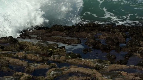 Ocean wave crashes over rocks in slow motion Stock Footage 104277830