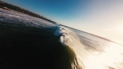 Ocean wave crashes toward shore, sun glints above Stock Footage 339787793